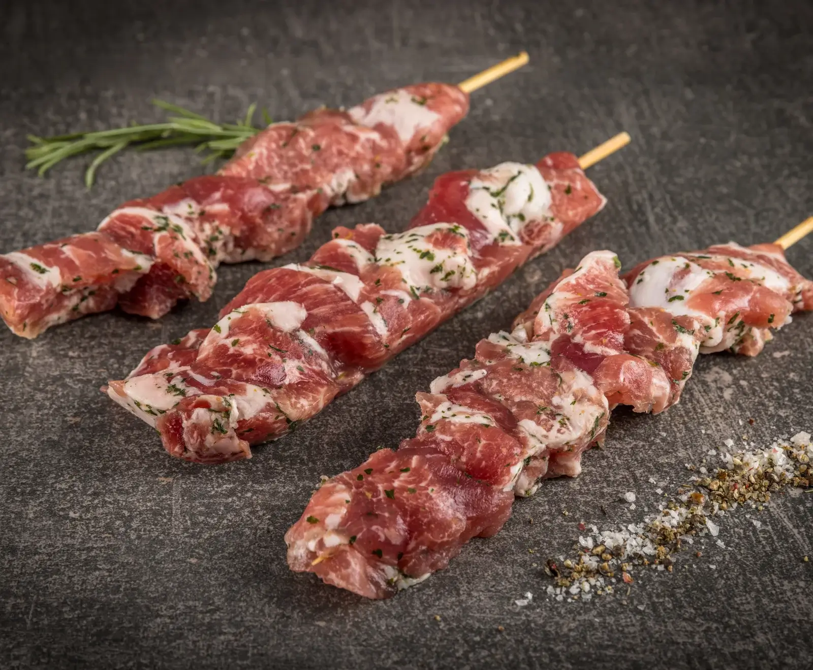 Rohe Lammfleischspieße mit Rosmarin gewürzt auf dunklem Hintergrund