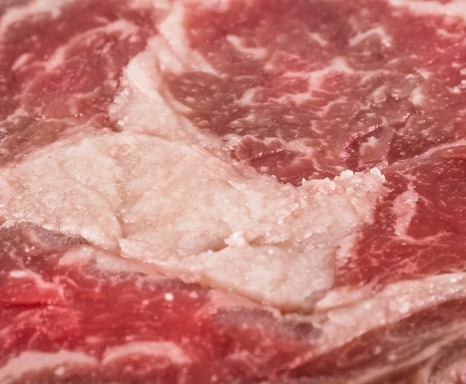 Nahaufnahme von rohem Rindfleisch mit deutlicher Marmorierung aus rotem Muskelfleisch und weißem Fett.