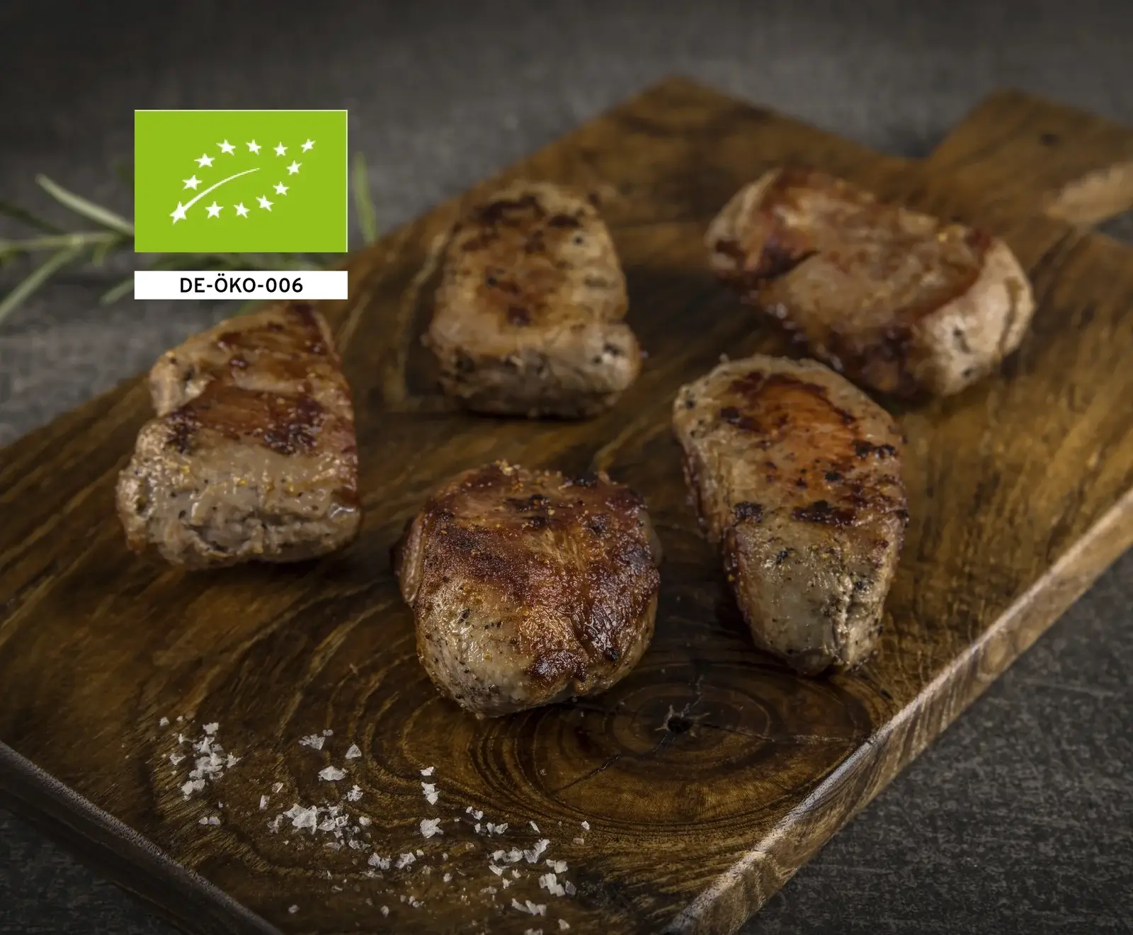 Mehrere kleine, runde, braun gebratene Fleischstücke auf einem Holzbrett mit Salzkristallen drum herum.