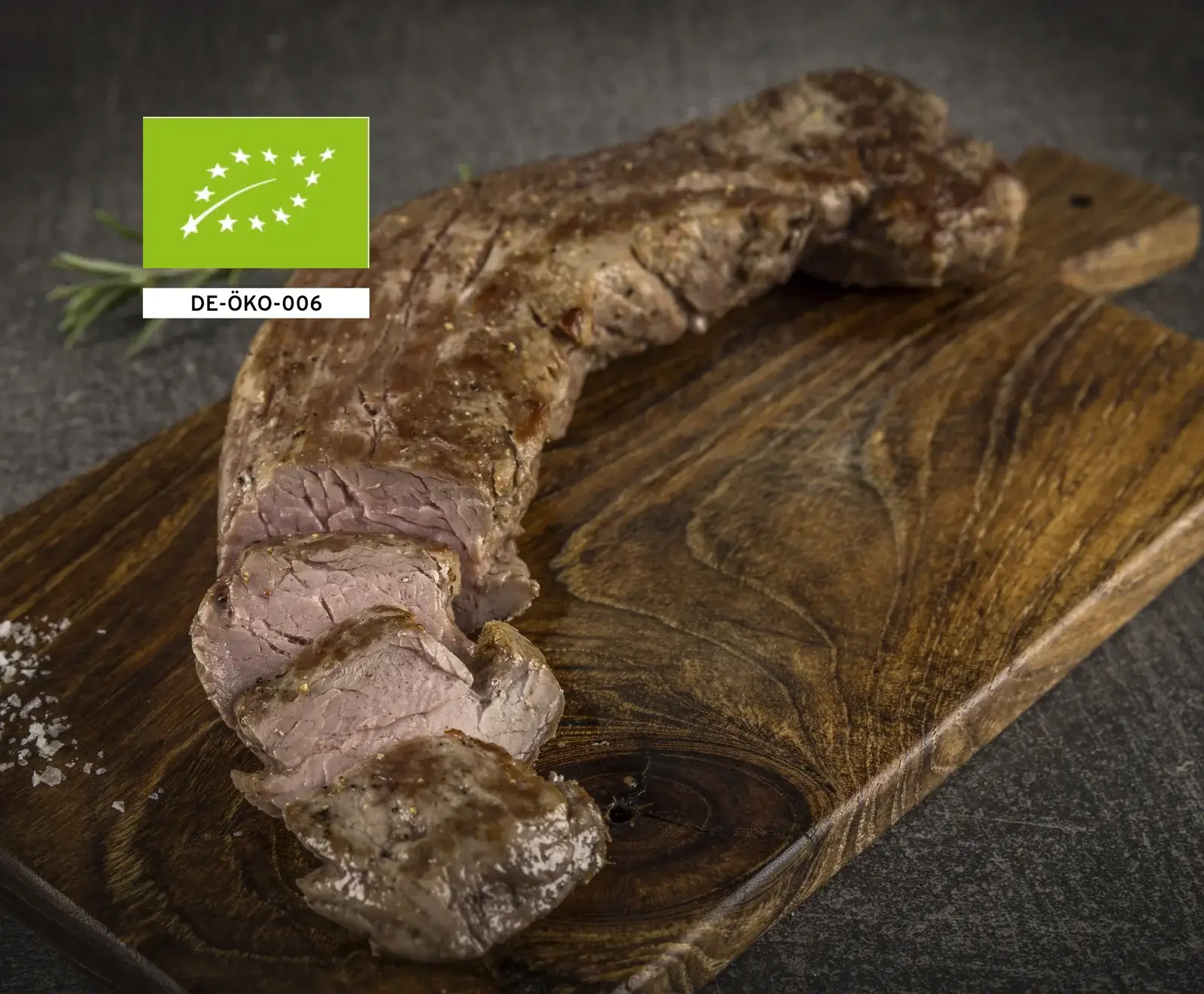 Bio Rinderfilet auf einem Holzbrett, garniert mit Rosmarin