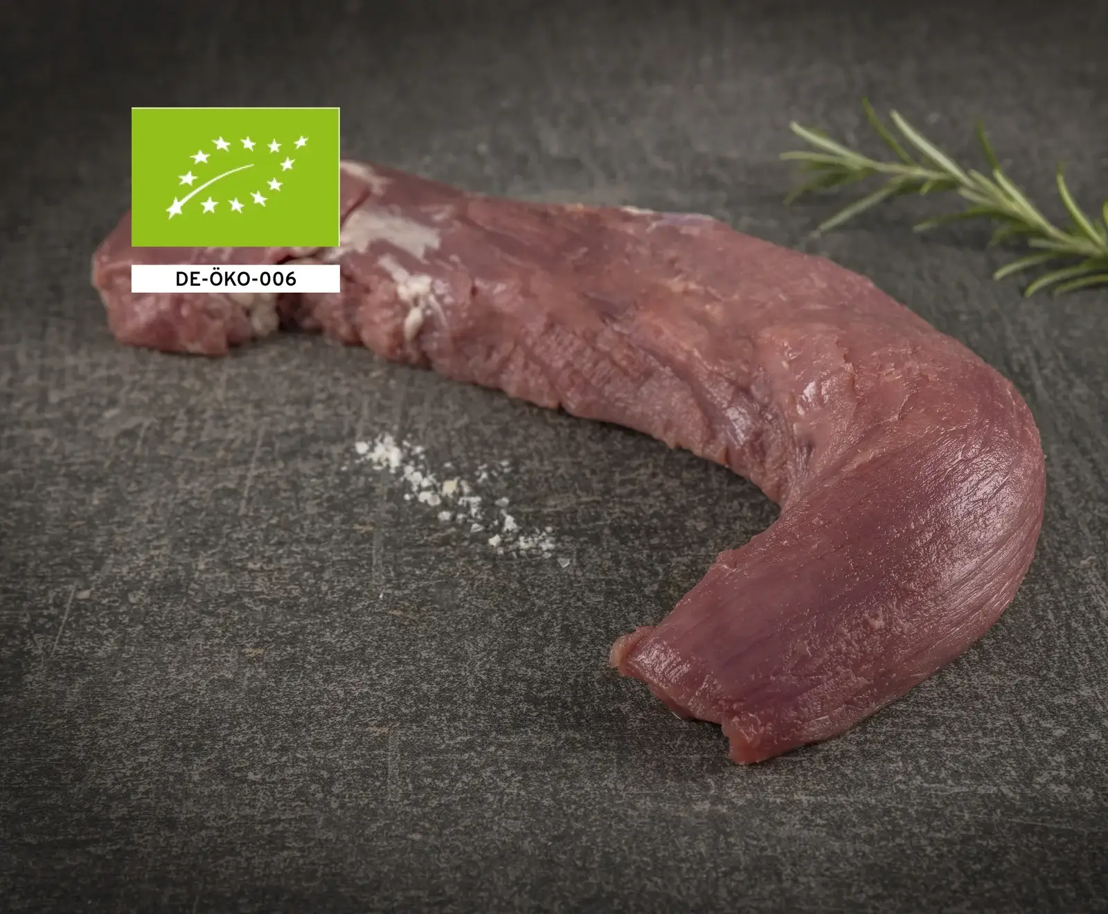Bio-Rinderfilet auf dunklem Hintergrund mit Rosmarin und EU-Bio-Siegel