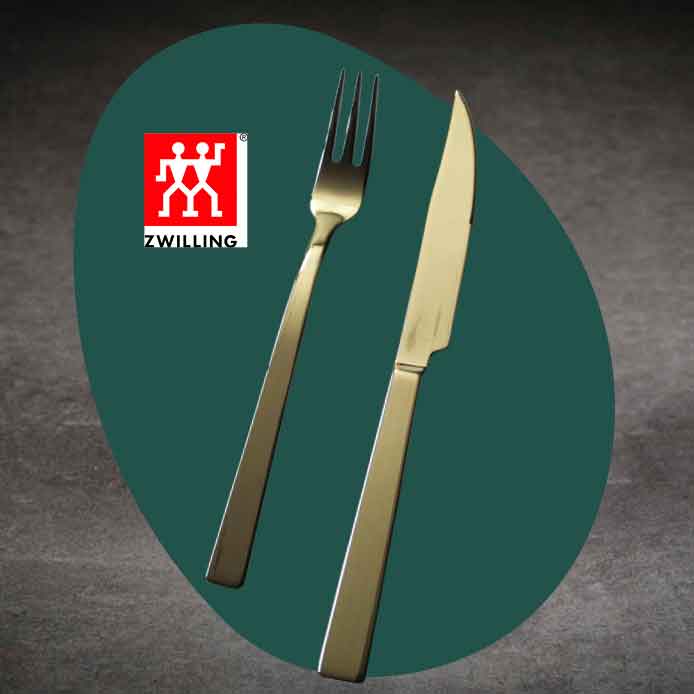 Das rote Zwilling Logo mit Schriftzug über einer goldenen Gabel und einem goldenen Messer, die auf einem dunkelgrünen Kreis vor einem grauen Hintergrund liegen.