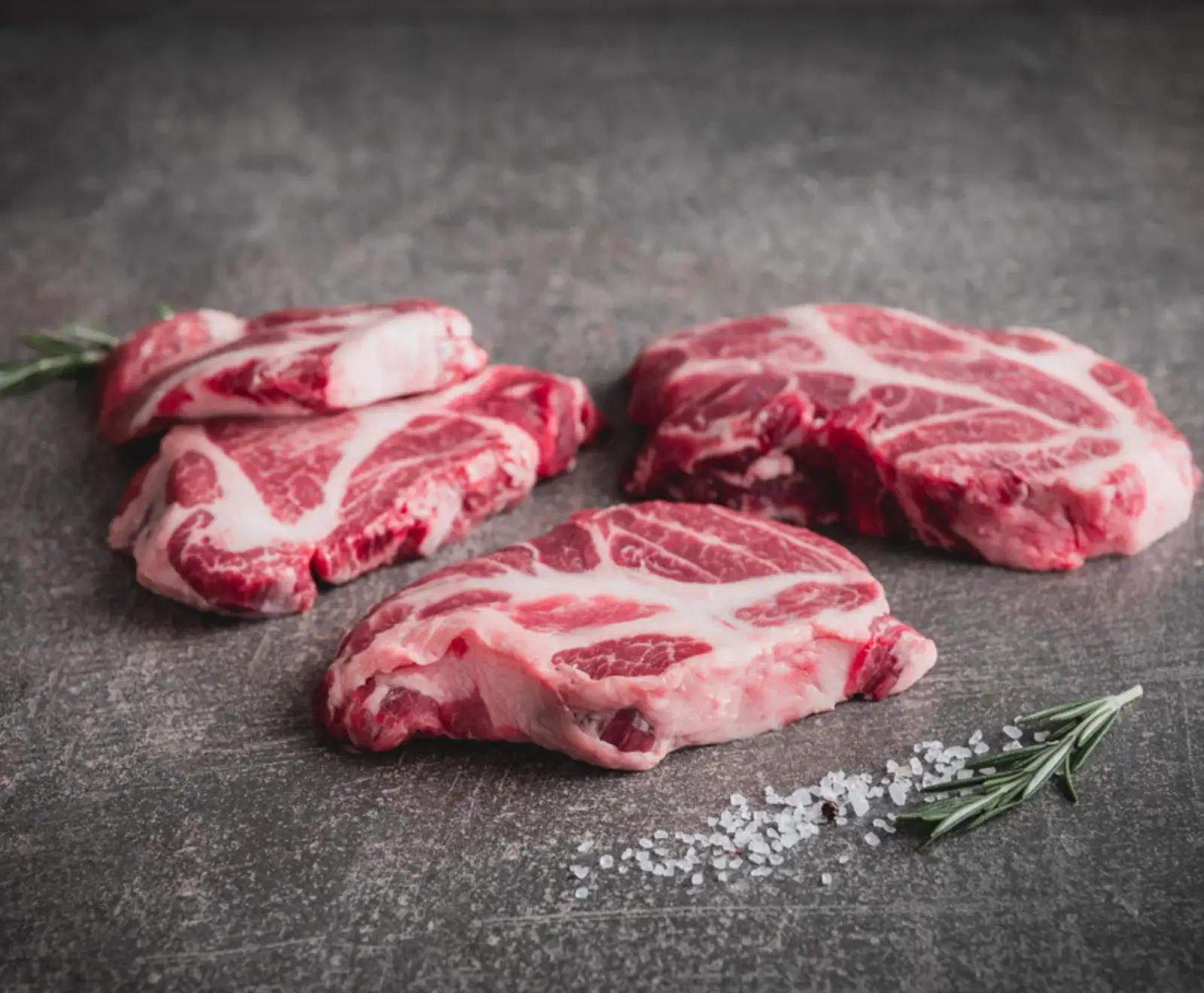 Rohe Rindfleischsteaks mit Fettmarmorierung und Meersalz auf dunklem Hintergrund