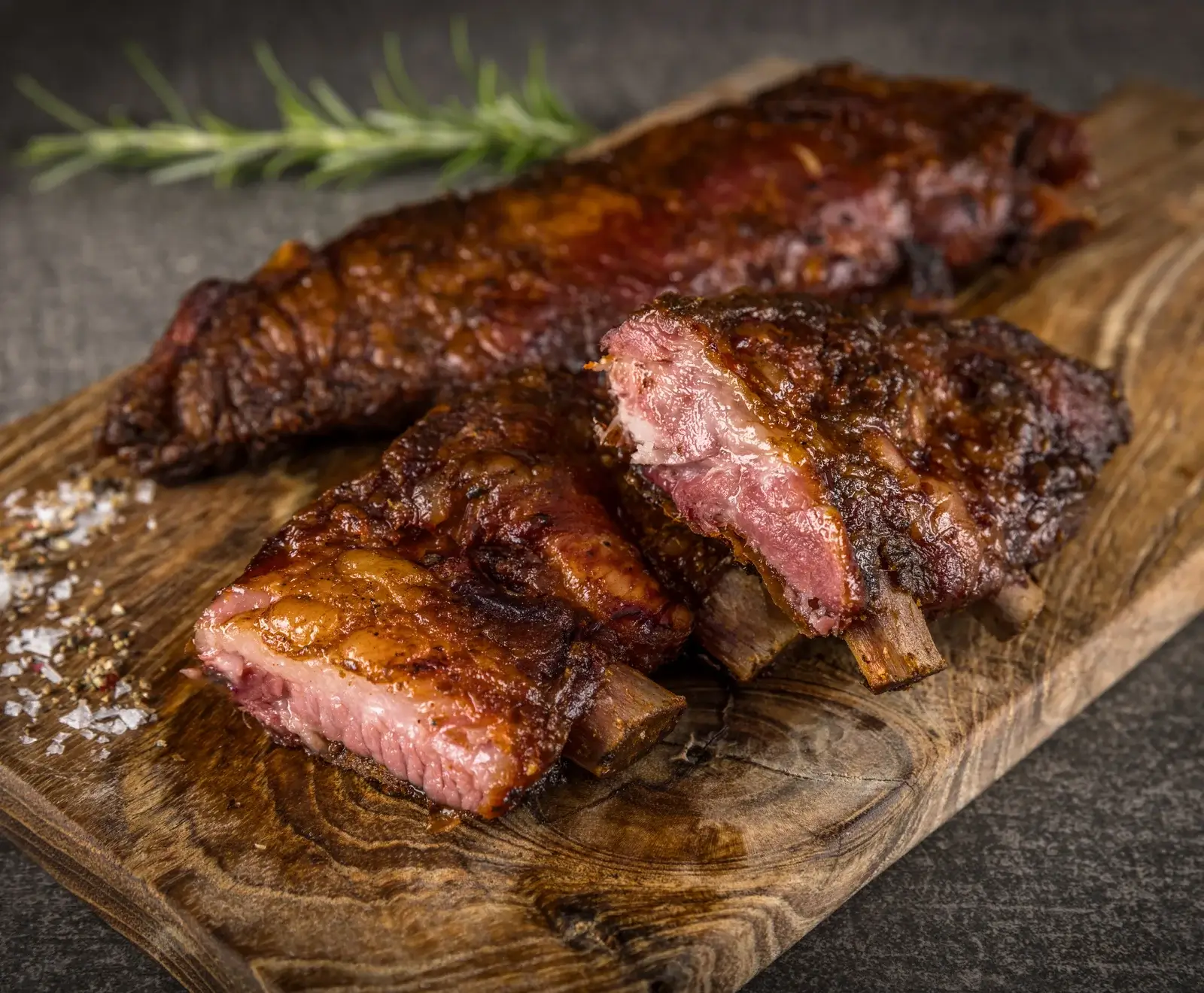 Gegrillte Steaks mit perfekter Kruste und rosa Inneren, serviert auf einem Holzbrett mit Rosmarin garniert.